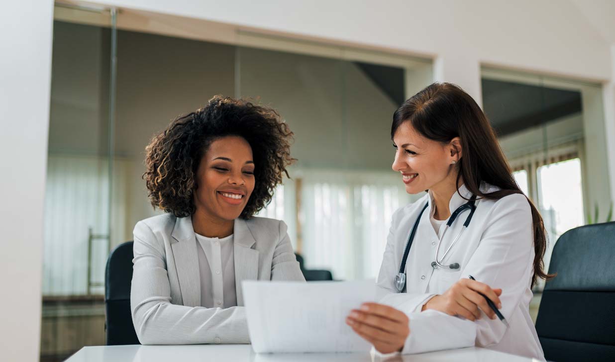 Smiling female patient and doctor looking at paper document
